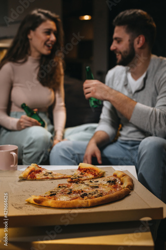 close of couple eating pizza at home