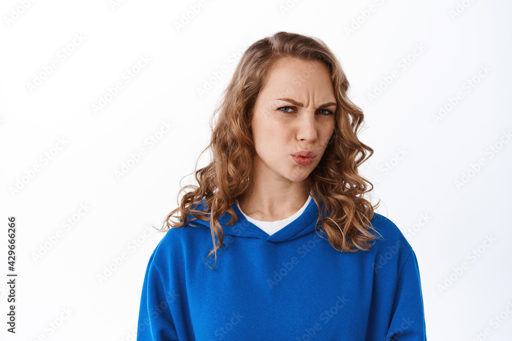Girl cringe from something awful. Disgusted blond girl grimacing, frowning and staring at unplesant embarrassing thing, standing against white background Girl cringe from something awful. Disgusted blond girl grimacing, frowning and staring at unplesant embarrassing thing, standing against white background
