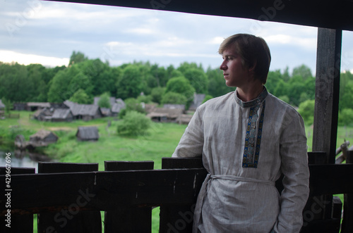 Downshifting concept. A young guy in national clothes lives in an eco-village and earns money from it