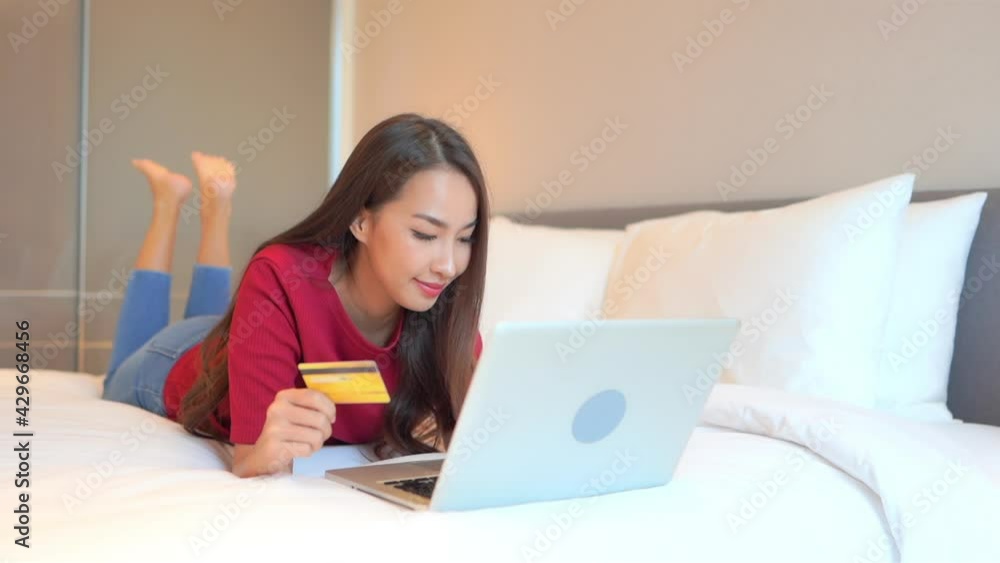 Girl Laying on Bed Entering Credit Card Details for Online Payment. Girl Laying on Bed Entering Credit Card Details for Online Payment.