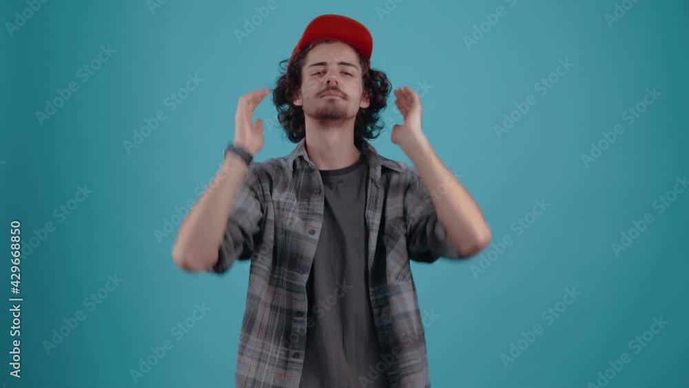 The charismatic young man puts his cap on his head, arranges his hair and gives confident eyebrows. Isolated on black background, Concept of life. People's emotions. 4k portrait The charismatic young man puts his cap on his head, arranges his hair and gives confident eyebrows. Isolated on black background, Concept of life. People's emotions. 4k portrait