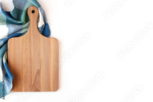 Wooden cutting board on blue napkin and white concrete background