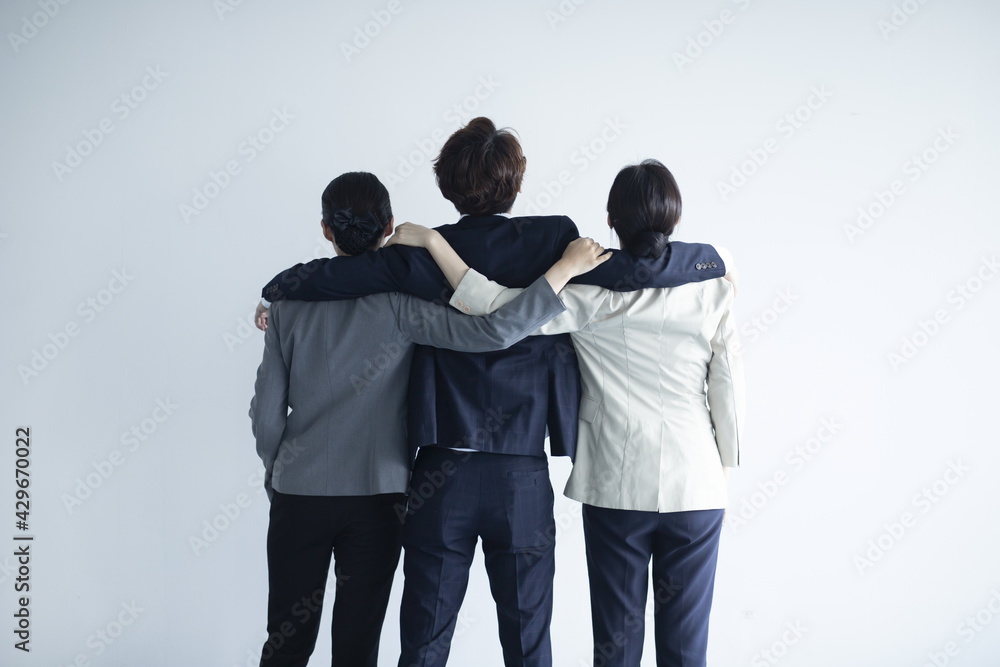 Business people standing together against white wall