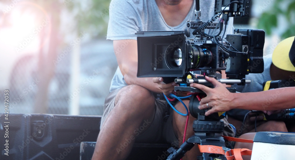 Blurry image of behind the scenes. Film Production crew team setting camera for shooting movie or online video. Outdoor shooting with professional camera. Blurry image of behind the scenes. Film Production crew team setting camera for shooting movie or online video. Outdoor shooting with professional camera.