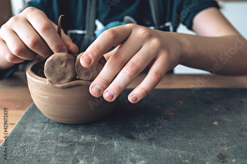 Hands of a young artist, modeling a clay bowl in art studio.  Traditional pottery craft. Ceramics workshop concept