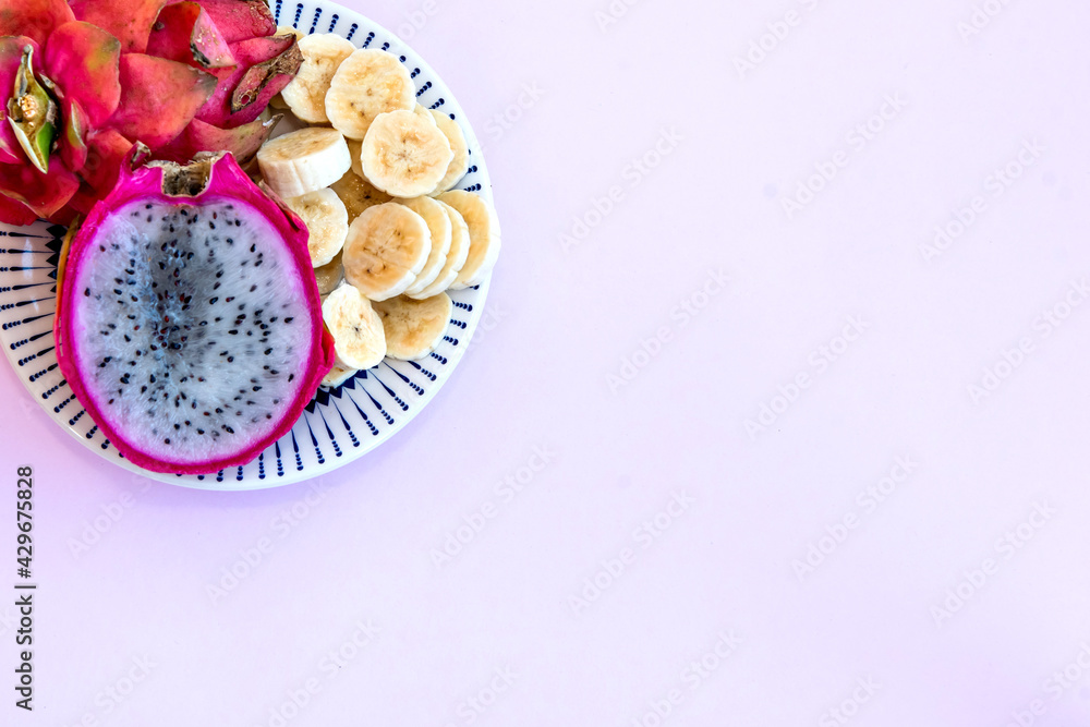 Plate with sliced bananas and pitaya cut in half. Top view. Plate with sliced bananas and pitaya cut in half. Top view.