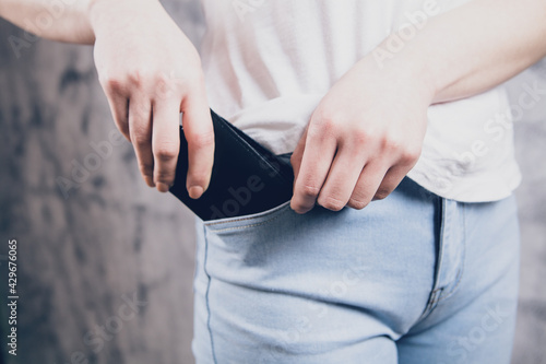 girl hand putting wallet in jeans pocket
