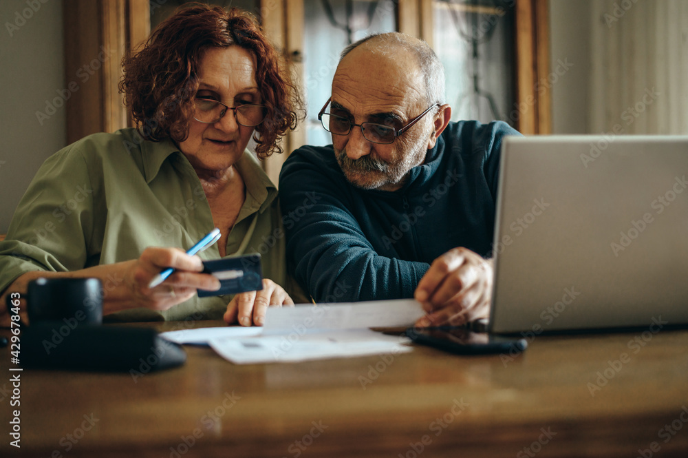 Senior couple using a laptop and a credit card at home Senior couple using a laptop and a credit card at home