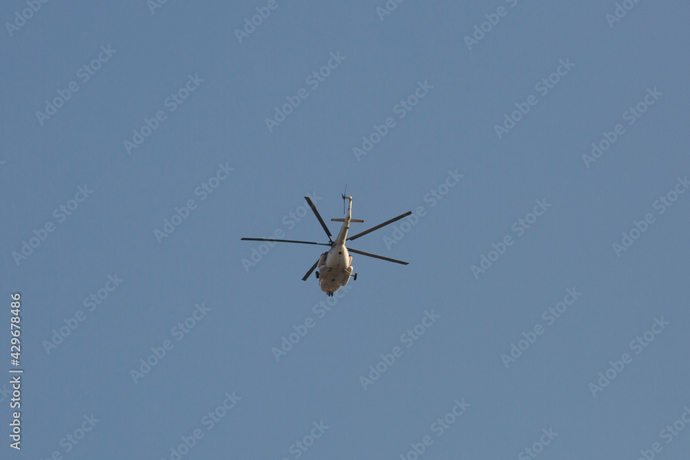 white helicopter flies away in the sky, rear view white helicopter flies away in the sky, rear view
