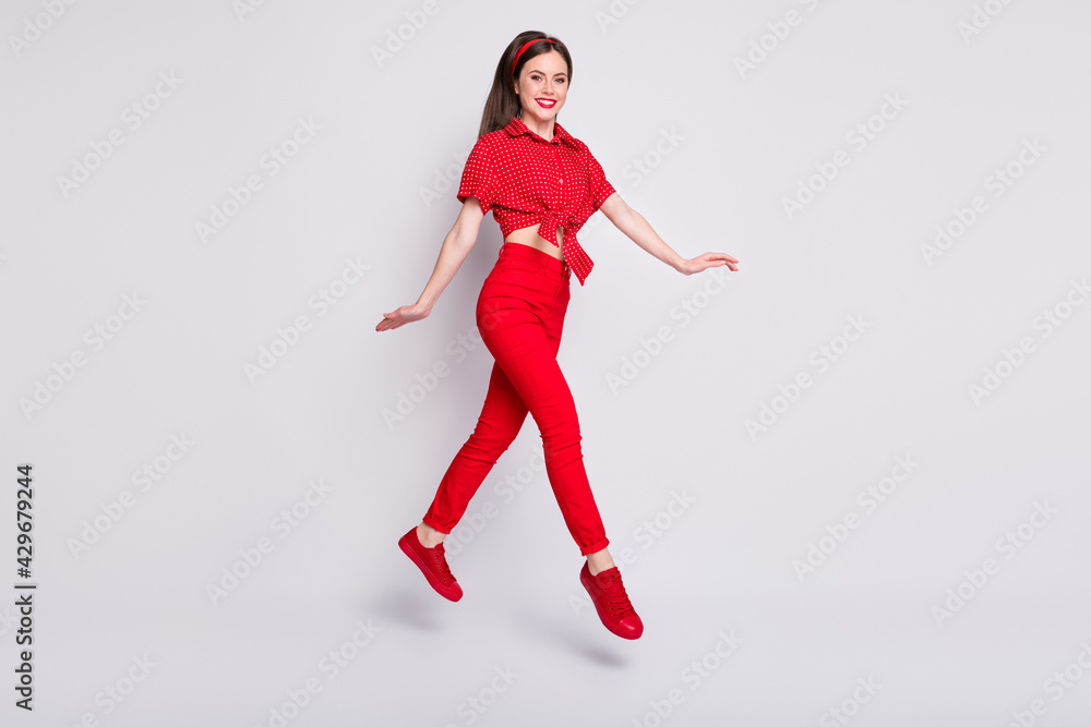 Full length photo of funny girl jump step wear red dotted blouse pants shoes isolated grey color background Full length photo of funny girl jump step wear red dotted blouse pants shoes isolated grey color background