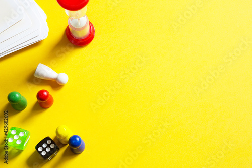 Layout of board games on a yellow background: dice, chips, hourglass timer. Entertainment at home for children and adults. Copy space photo