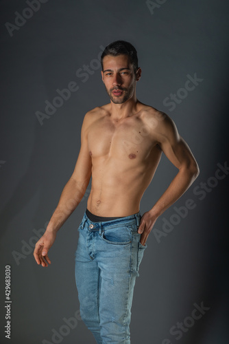 Studio portrait of a shirtless sexy man with abs in denim blue jeans