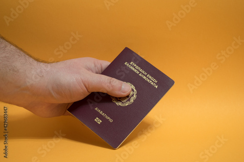 Hand of a young man holding Greek passport document