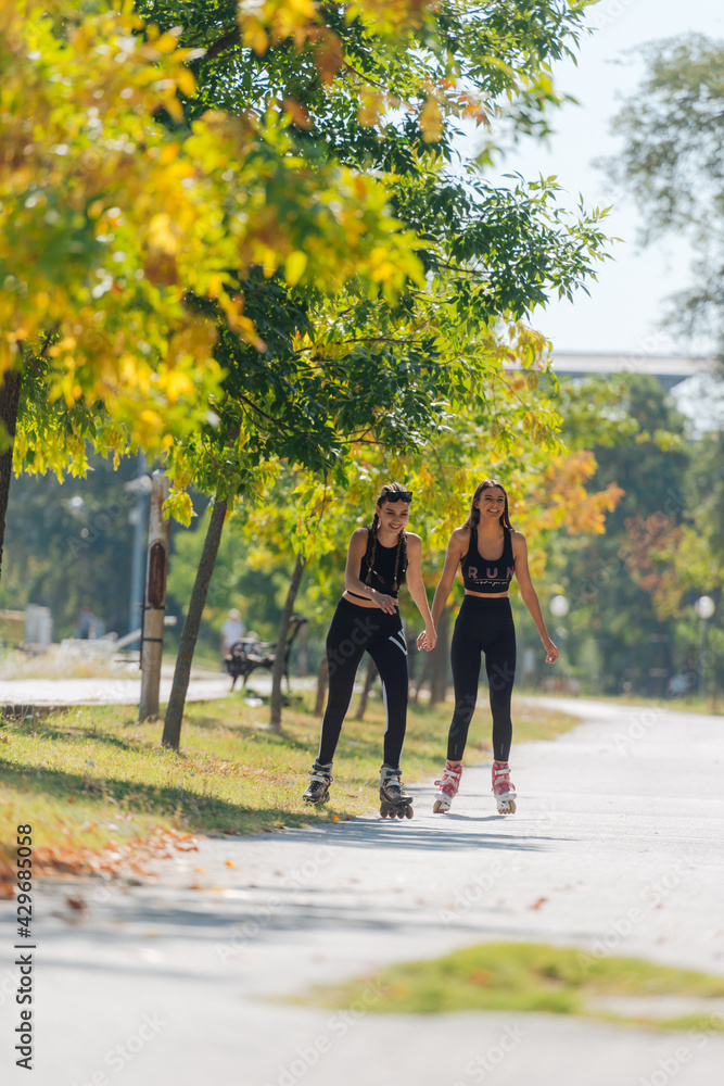 Obraz premium Full-length picture of sexy sportswomen rollerskating in the park