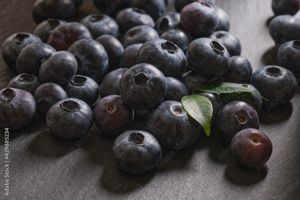 Fototapeta premium Fresh blueberries are scattered on a dark stone background. Products for a healthy diet. A source of vitamins. 