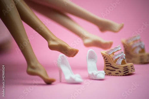 Fotografia Closeup of feet of mannequin dolls with shoes on pink background - Fashion victi