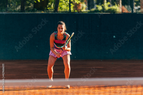 Female tennis player waiting to return serve playing a tennis game on a clay court. © qunica.com