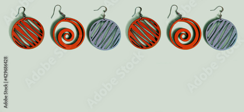 Above hang earrings made of wood on a mint background. Handmade.
