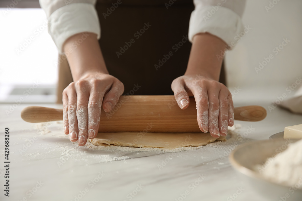 Woman rolling dough at table in kitchen, closeup Woman rolling dough at table in kitchen, closeup