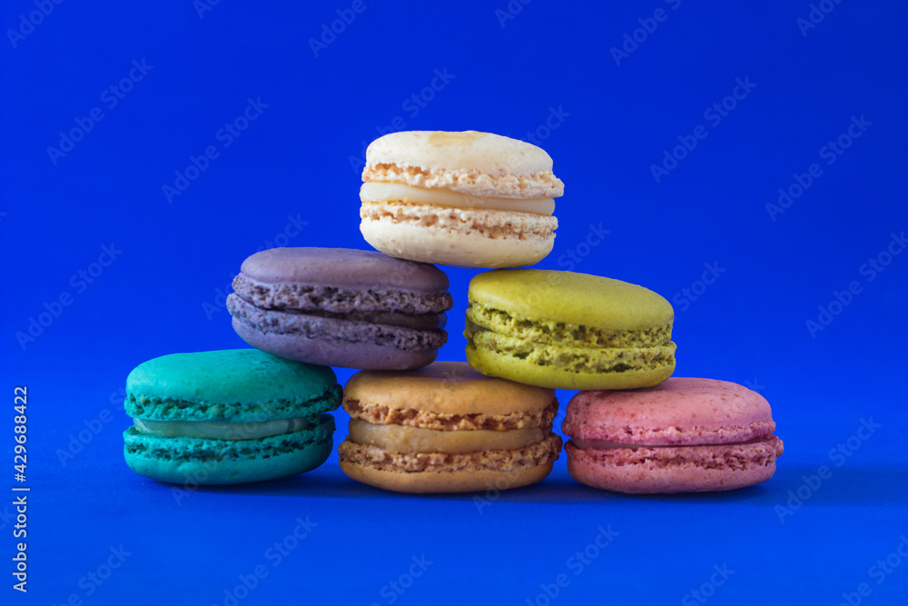 Colorful macaroons in a pile isolated on a blue background. Colorful macaroons in a pile isolated on a blue background.