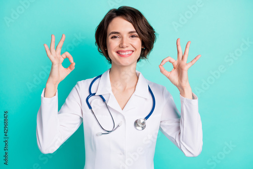 Photo of young woman happy positive smile doctor clinic show okey perfect sign ad isolated over teal color background