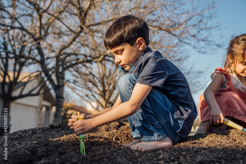 Happy boy and girl digging in pile of dirt