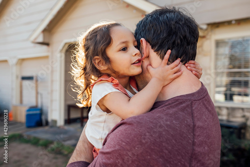 Girl in whispering secret in dad's ear