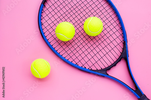 Tennis racket with balls on pink background.