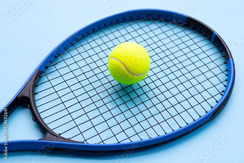 Tennis racket with ball on blue background. © Bowonpat