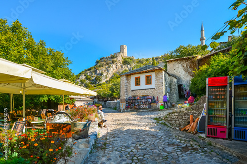 A dog sits outside the outdoor seating for a cafe in the medieval city of Pocitelj Capljina under the Kula tower in Bosnia and Herzegovina photo