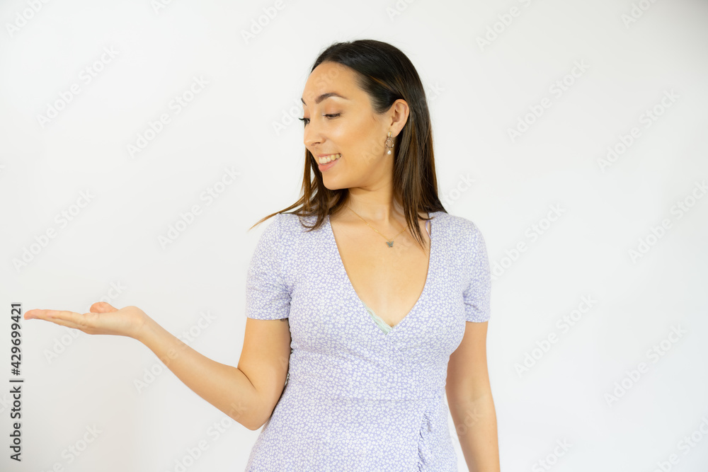 Young woman over isolated background holding something with hand, product presentation. Young woman over isolated background holding something with hand, product presentation.