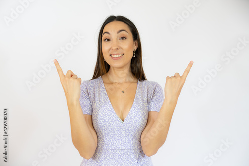 Portrait of beautiful young woman pointing up over white background.