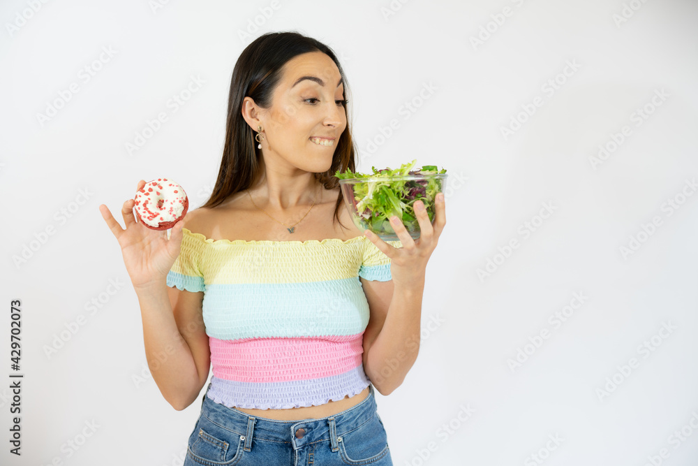 Portrait of a happy playful woman holding donuts and salad isolated over white background. Portrait of a happy playful woman holding donuts and salad isolated over white background.