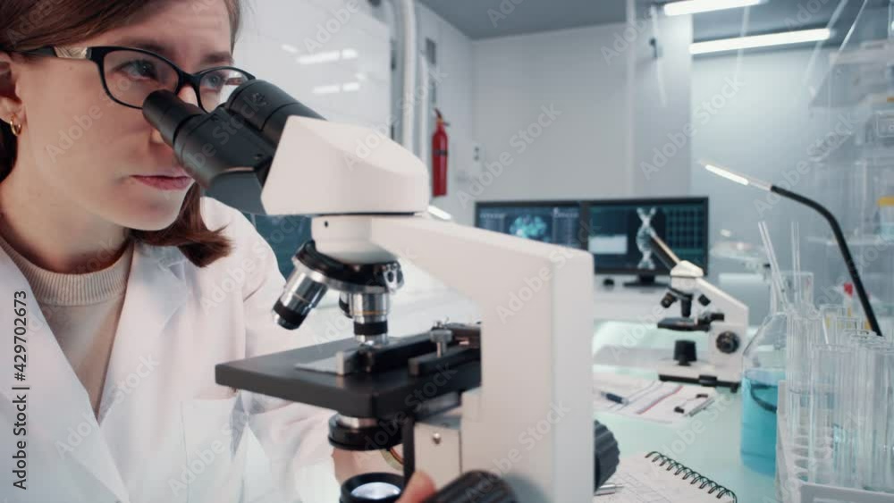 Young female doctor working with pathogen samples. Using microscope Young female doctor working with pathogen samples. Using microscope
