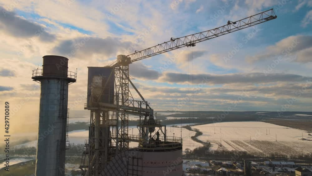 Aerial view of cement plant with high factory structure and tower crane at industrial production area at sunset. Aerial view of cement plant with high factory structure and tower crane at industrial production area at sunset.