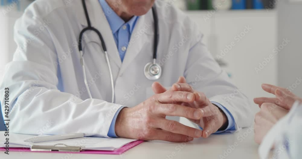 Close up of patient and doctor hands in medical office on table Close up of patient and doctor hands in medical office on table
