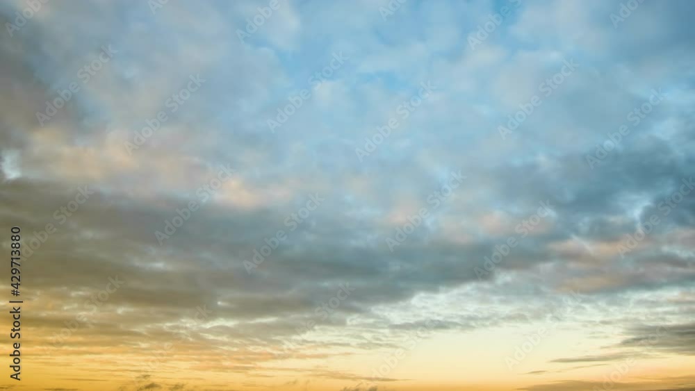 Time lapse with fast moving clouds on blue sky at sunset.