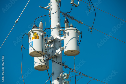 Electric pole and electric transformer on background clear blue sky. Electrical power lines. High voltage metal cable. Good for Electric Company job, news, advertising, billboards.  photo