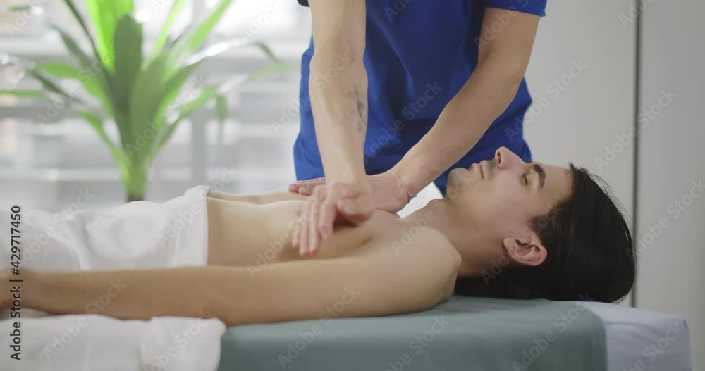 Professional masseur doing massage for young man in massage room. Professional masseur doing massage for young man in massage room.