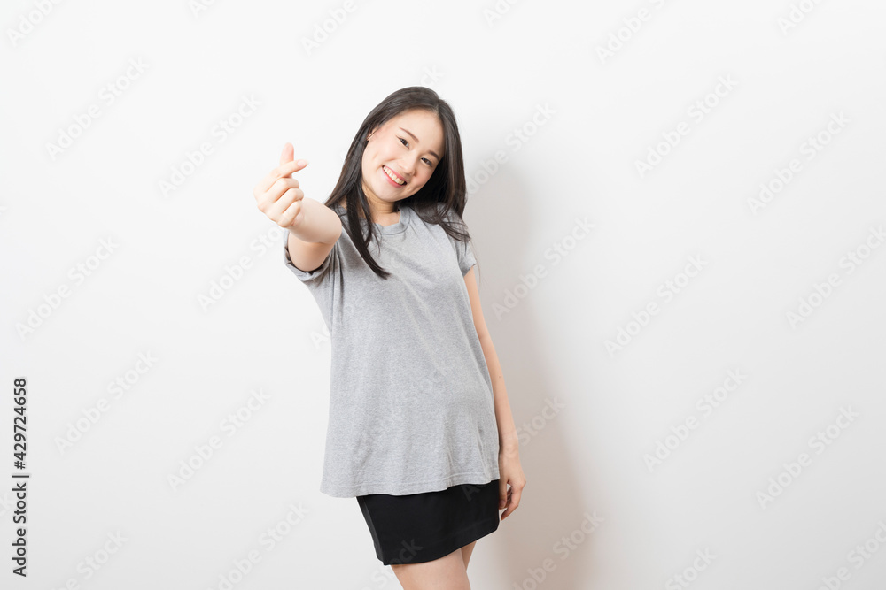 Portrait of happy young asian woman wearing grey shirt smiling at camera while standing over white background. Portrait of happy young asian woman wearing grey shirt smiling at camera while standing over white background.