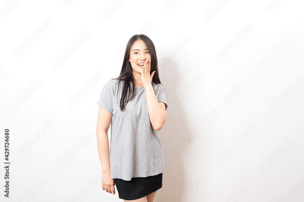 Portrait of happy young asian woman wearing grey shirt smiling at camera while standing over white background. Portrait of happy young asian woman wearing grey shirt smiling at camera while standing over white background.