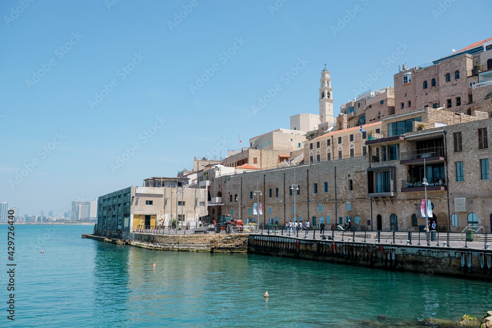 Old town and port of Jaffa and modern skyline of Tel Aviv city in blur background.