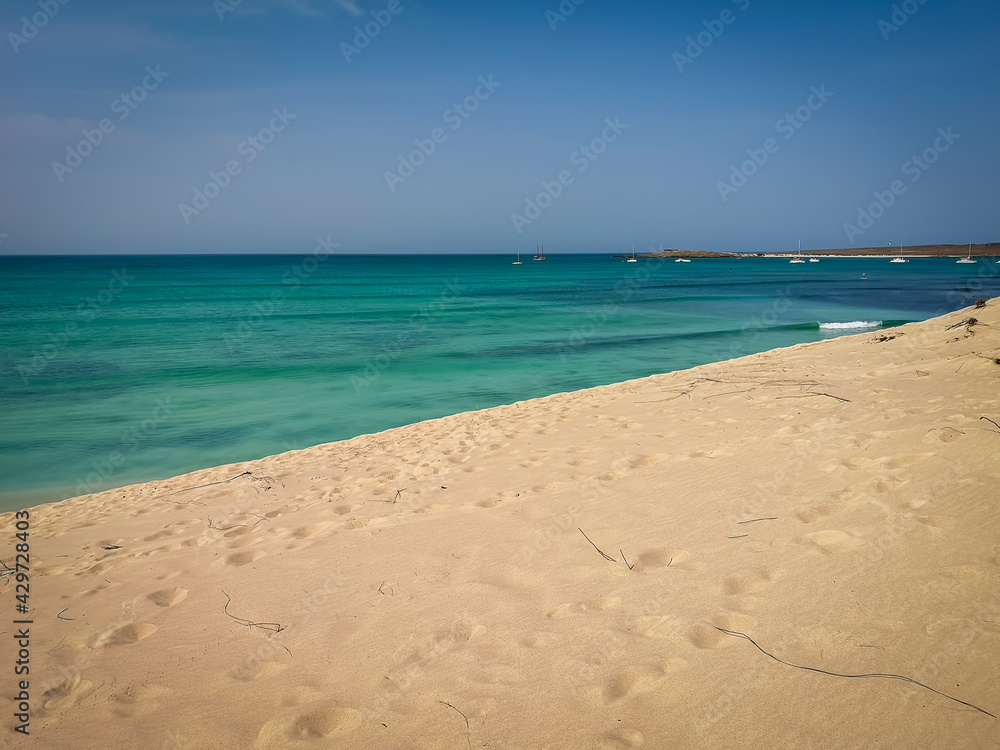 Tropical climate in Cape Verde, the island of Boa Vista. Calm Atlantic Ocean and hot day on a sandy beach. Selective focus on the horizon, blurred background.