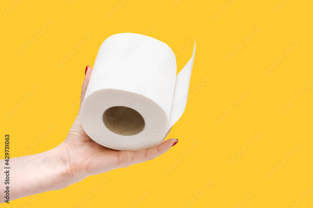 Toilet paper in hand. Roll of toilet paper in hand on a yellow background. Toilet paper in hand. Roll of toilet paper in hand on a yellow background.