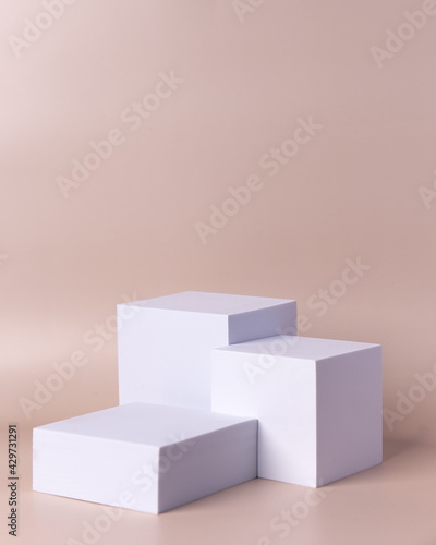 Three white cubes with beige background
