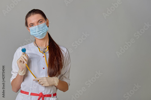 a doctor in a medical mask and white coat with a stethoscope around his neck photo