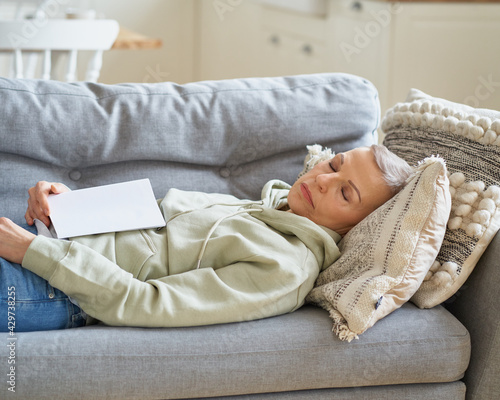Wallpaper Mural Senior grey haired woman sleeping on coach after reading book, having a nap while spending leisure time alone at home. Selective focus on senior female Torontodigital.ca