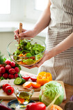 Beautiful young woman preparing delicious fresh vitamin salad. Concept of clean eating, healthy food, low calories meal, dieting, self caring lifestyle. Colorful vegetables, glass bowl. Close up