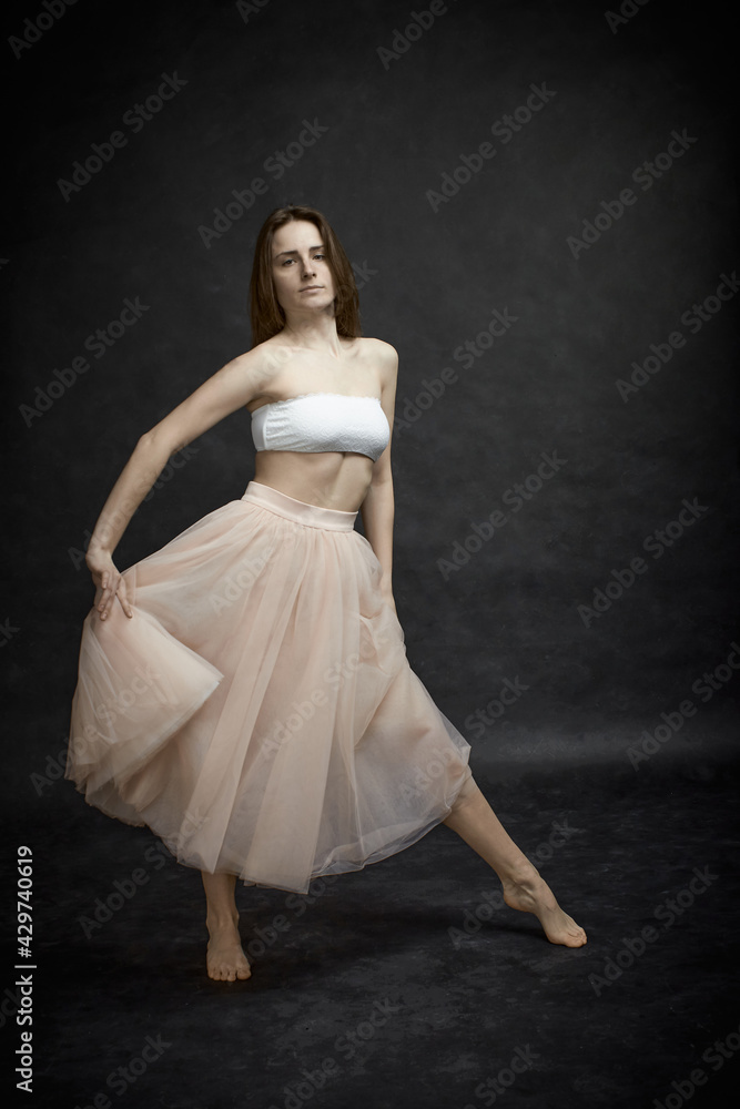 Fototapeta premium Young girl in white top and peach skirt dancing