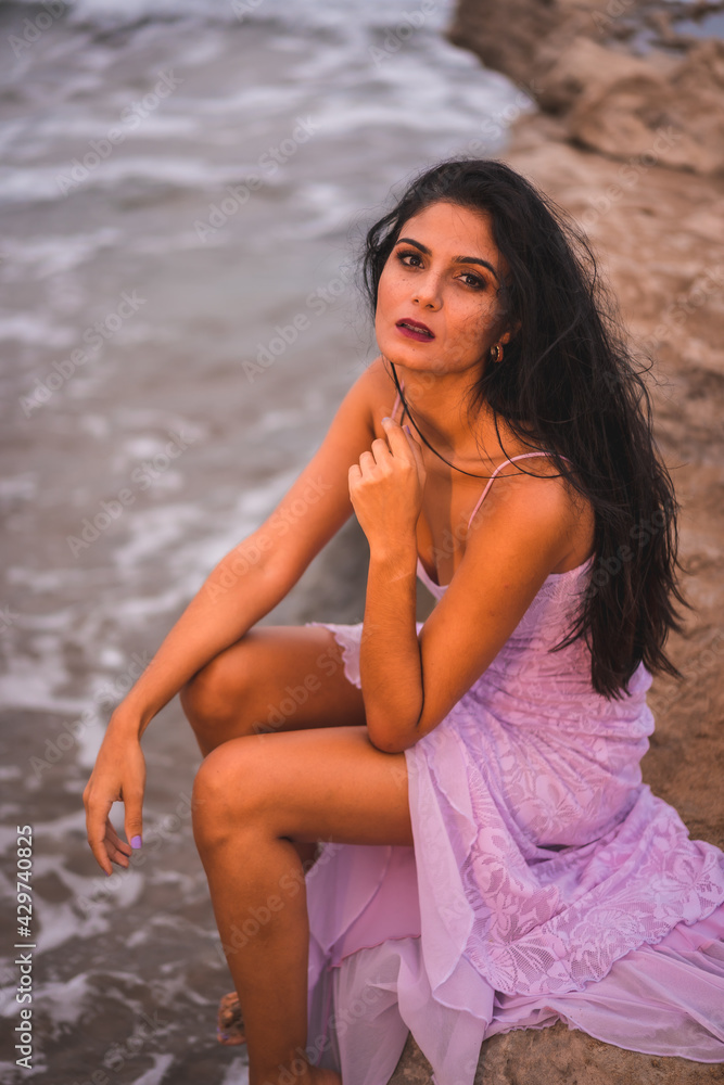 A young brunette Caucasian with a pink cloth dress, on the beach in the sea in Cabo de Gata, Nijar. Andalucia in Spain A young brunette Caucasian with a pink cloth dress, on the beach in the sea in Cabo de Gata, Nijar. Andalucia in Spain